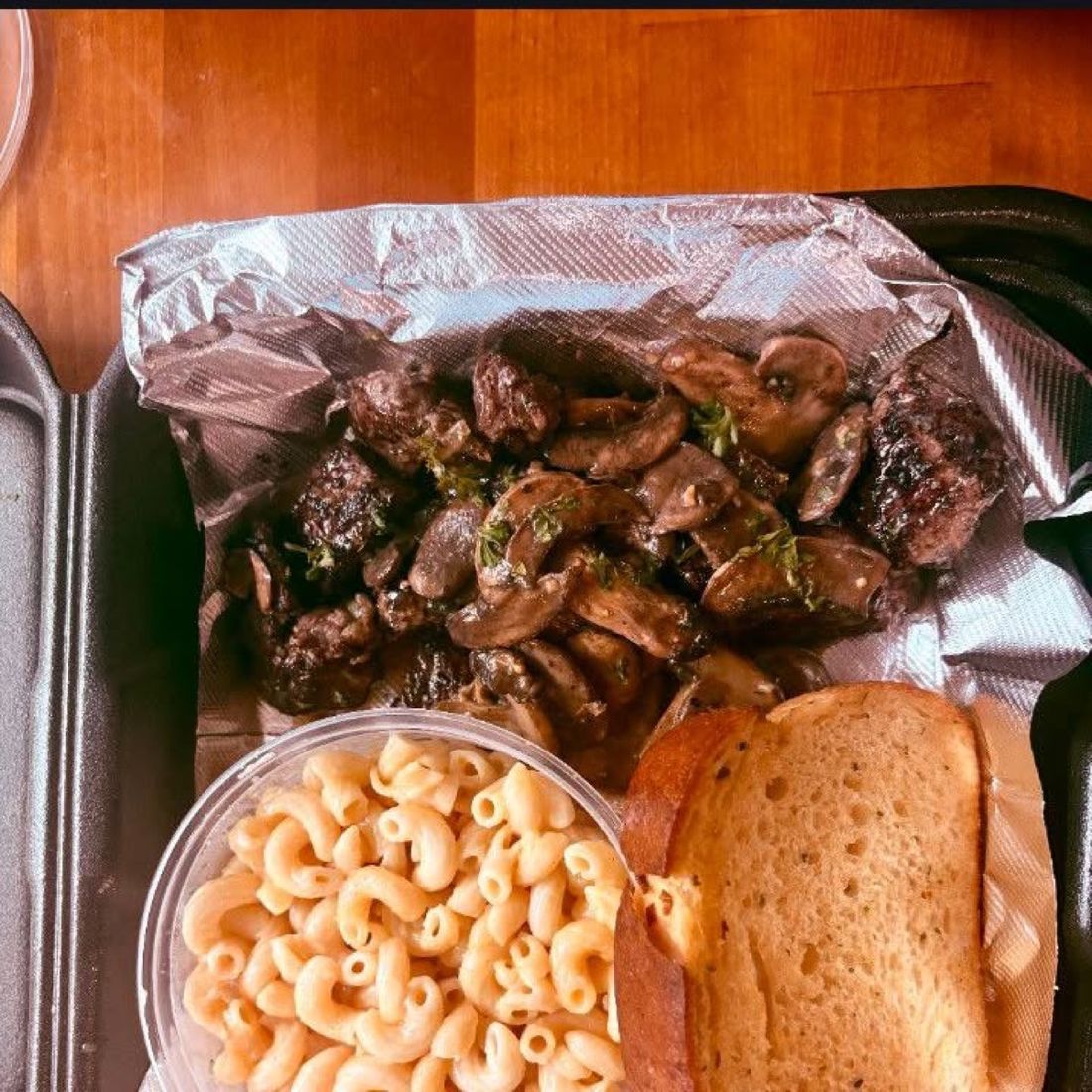 Char-grilled beef tips with a side of mac and cheese and garlic bread